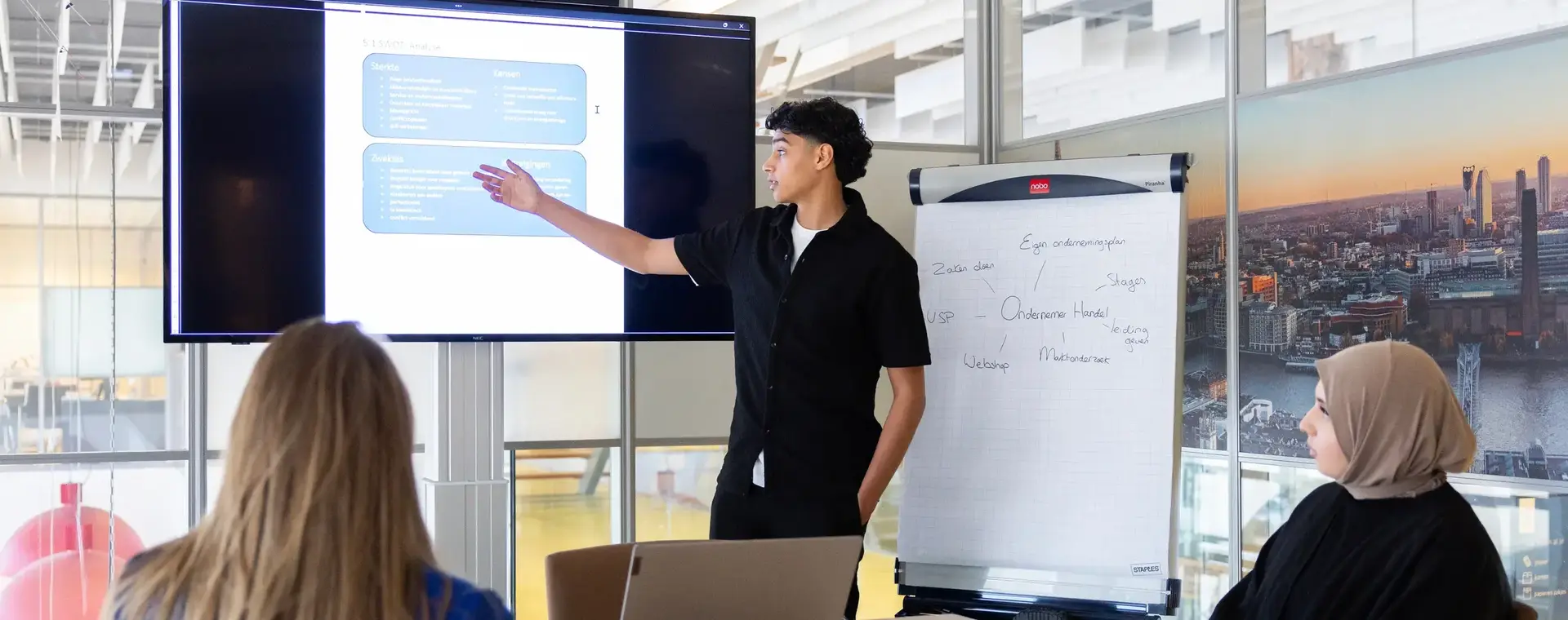 Student geeft presentatie aan twee personen aan vergadertafel