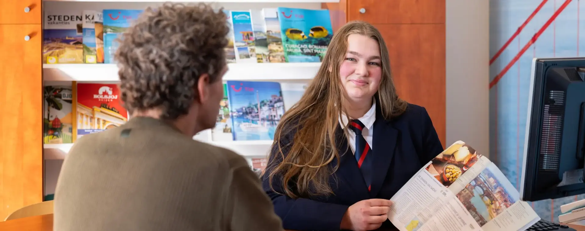 Studente laat reisbrochure aan klant zien